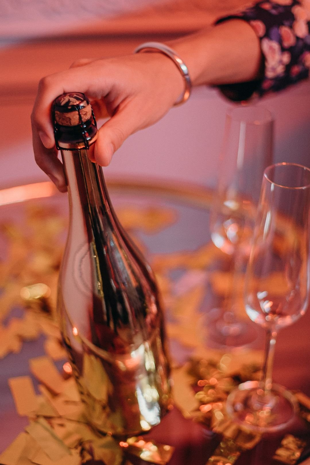 Bottiglia di champagne dorata aperta tra i coriandoli al tavolo